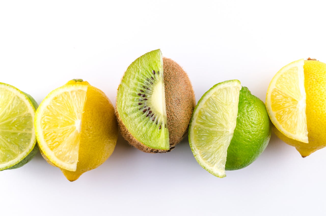 Colorful arrangement of kiwi, lemon, and lime slices showcasing freshness and vibrancy on a white background.